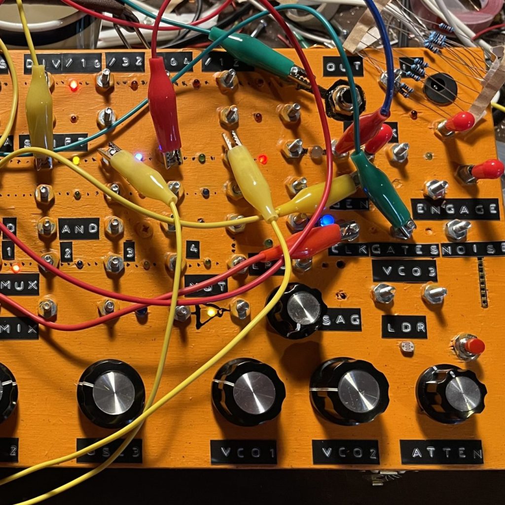 an orange synthesizer with knobs and tons of alligator clips